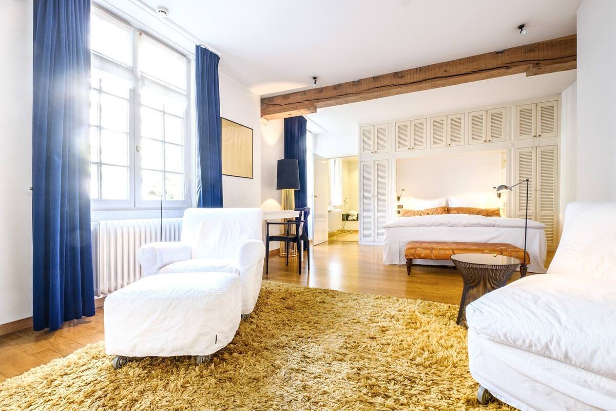 A spacious room with a large bed, a sofa, a small table, and a radiator.