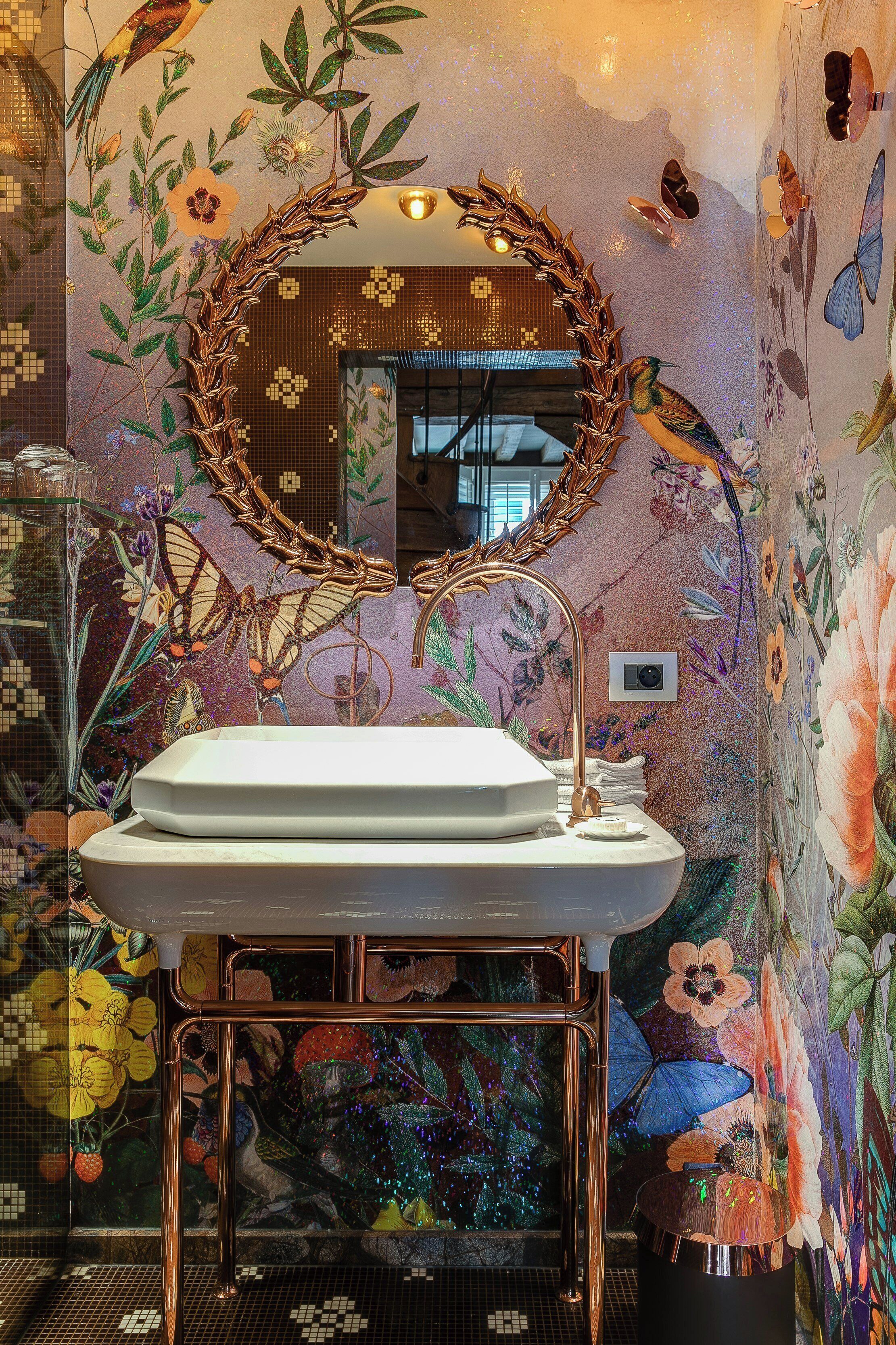 A bathroom with a floral mural, a round mirror, and a white sink.