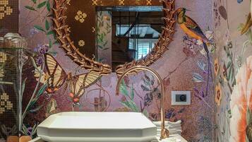 A bathroom with a floral mural, a round mirror, and a white sink.