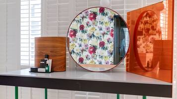 A modern room with a wooden desk, a round mirror with a floral pattern, and a wooden cabinet.