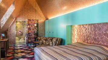 Een slaapkamer met een kamerbedekking met een patroon, een bed met een strepenbed overtrek, een stoel en een kledingkast.