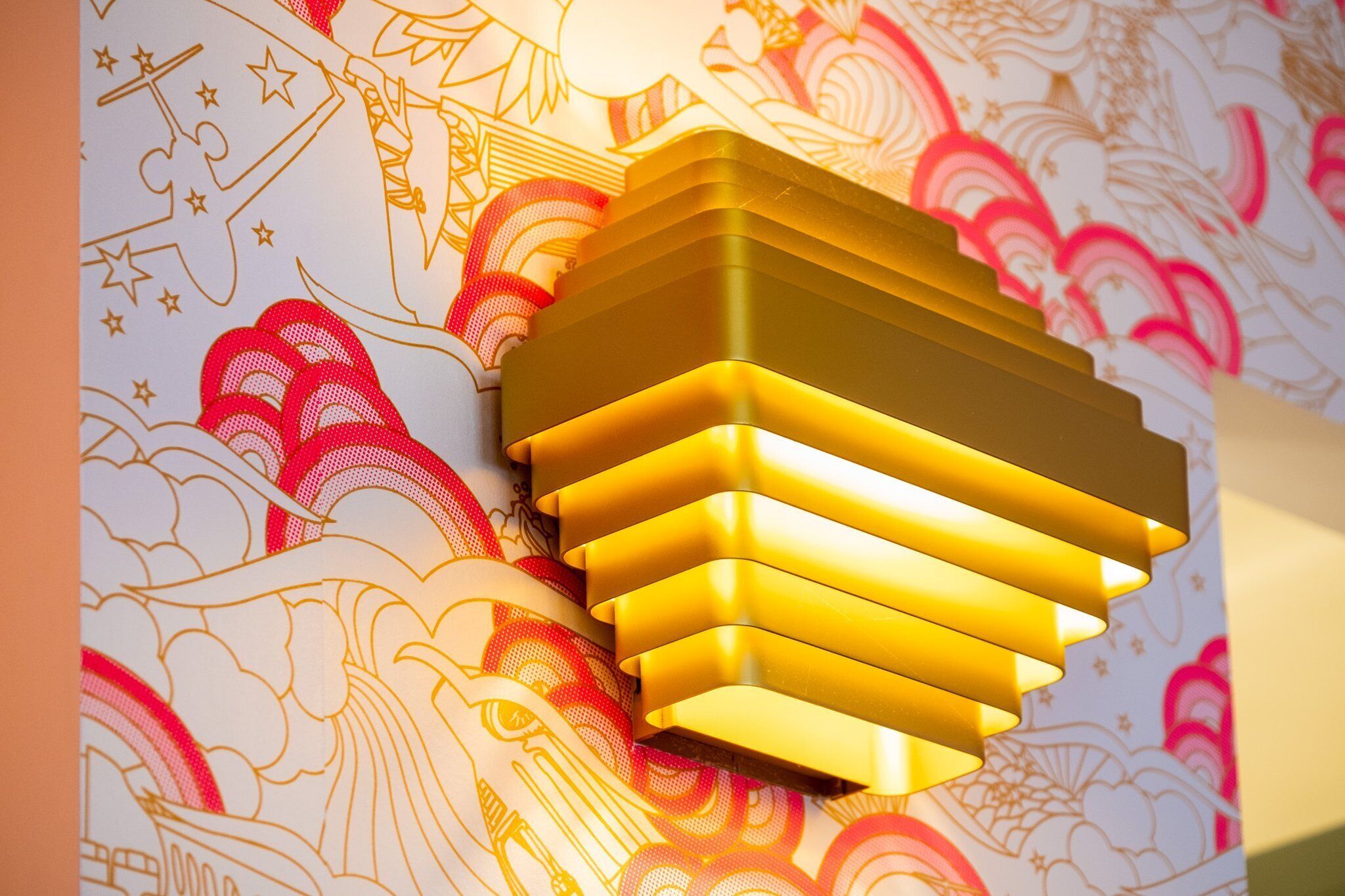 A wall with a decorative pattern and a modern light fixture.