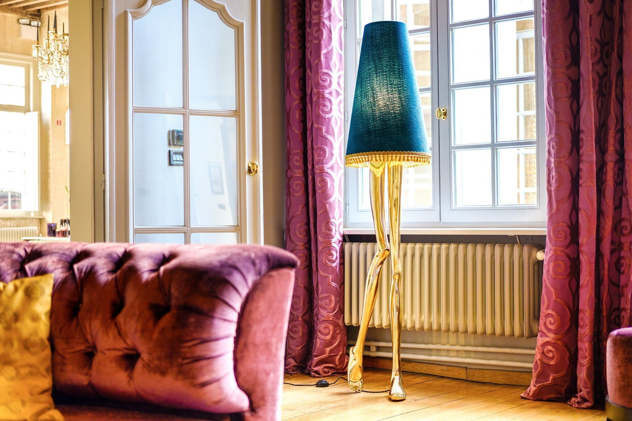 A room with a large window, a radiator, and a tall floor lamp.