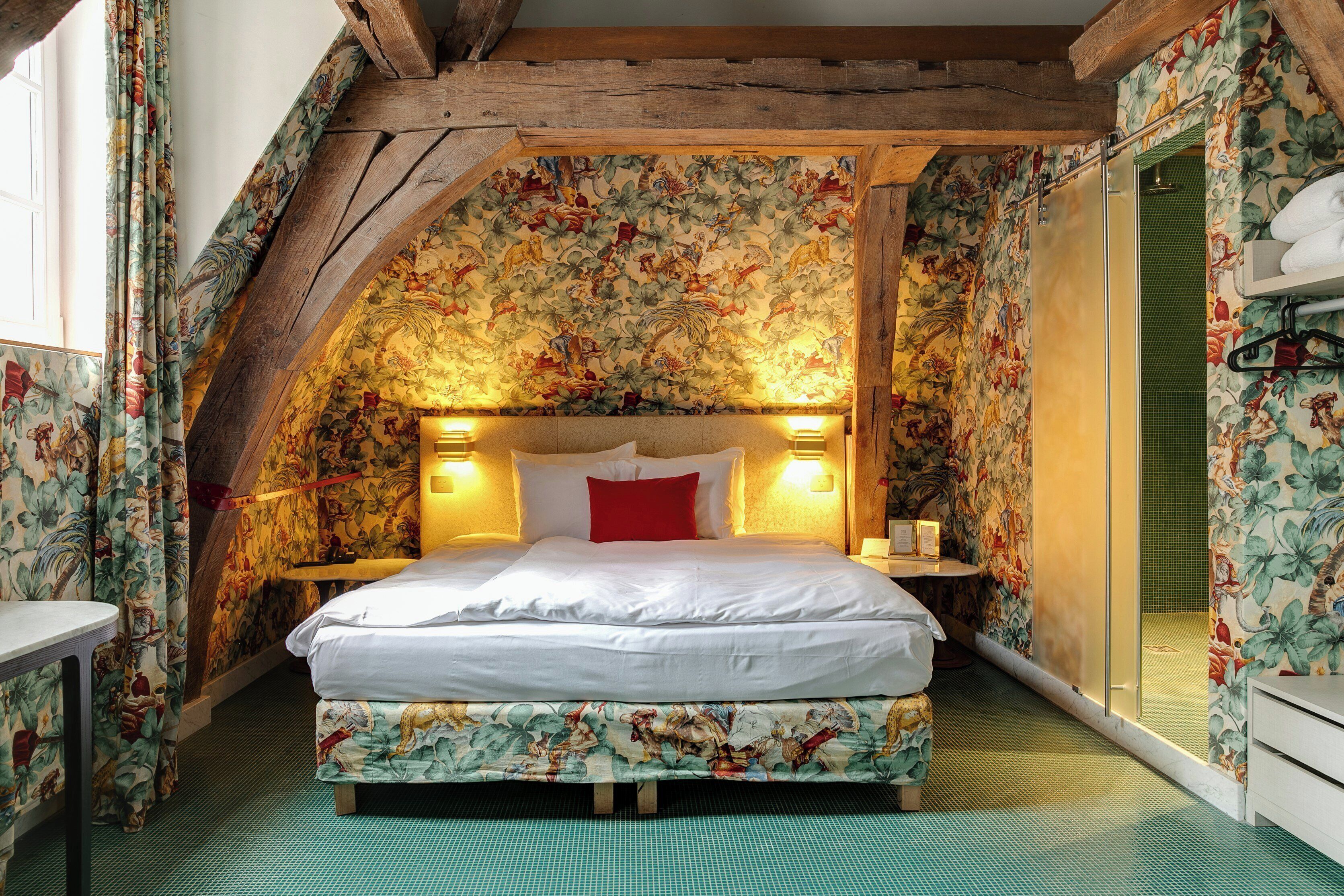 Un dormitorio con cama, papel tapiz floral, vigas de madera y suelo verde.