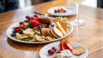 Una mesa con un plato de quesos variados, frutas y galletas.