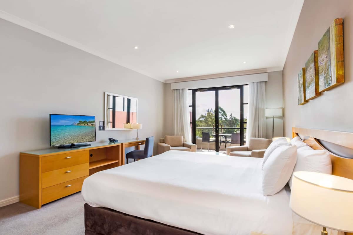 Habitació d'hotel amb llit, escriptori amb televisió, cadira i balcó amb vistes.