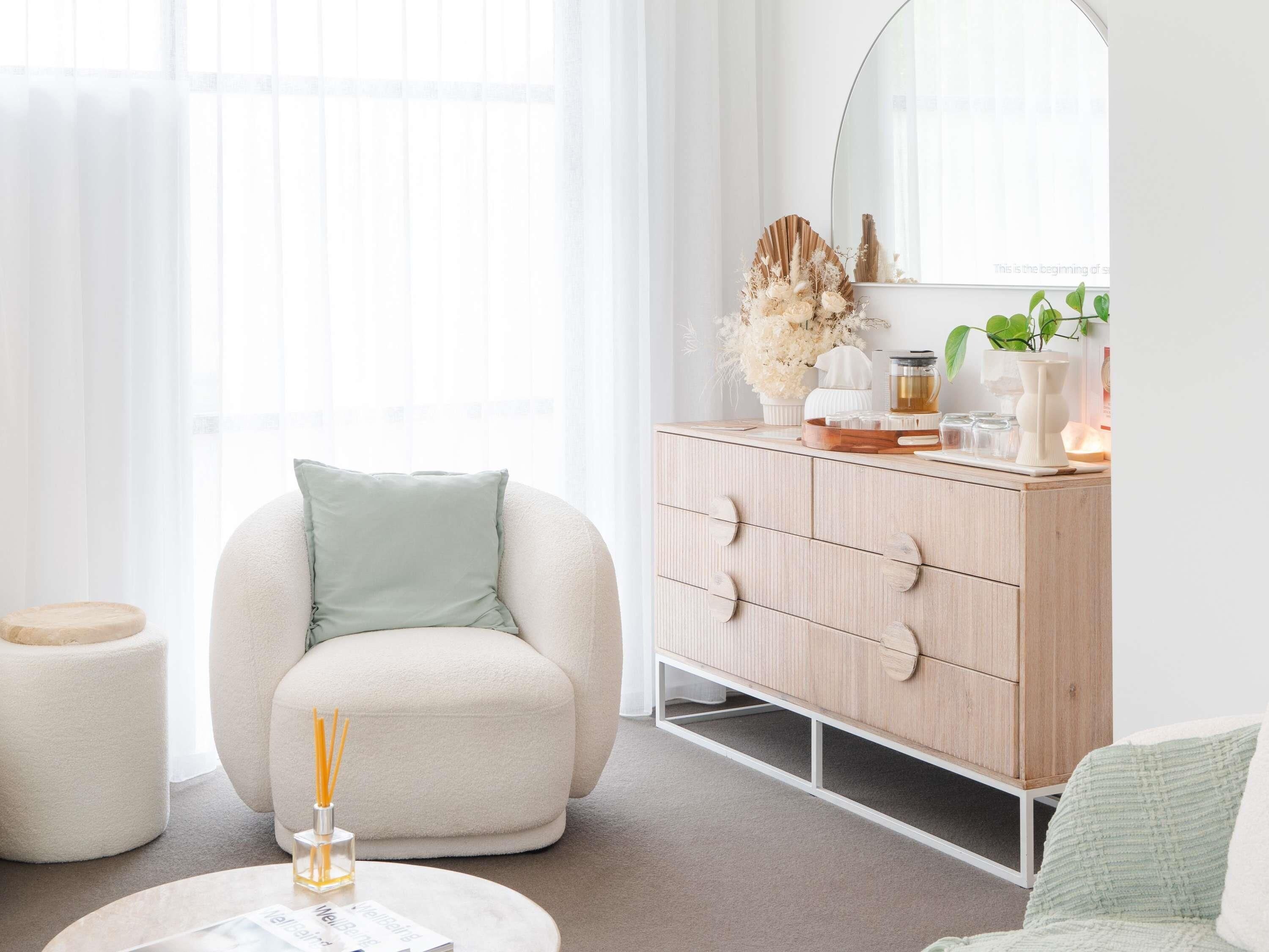 A modern living room with a round armchair, a wooden dresser, and a round coffee table.