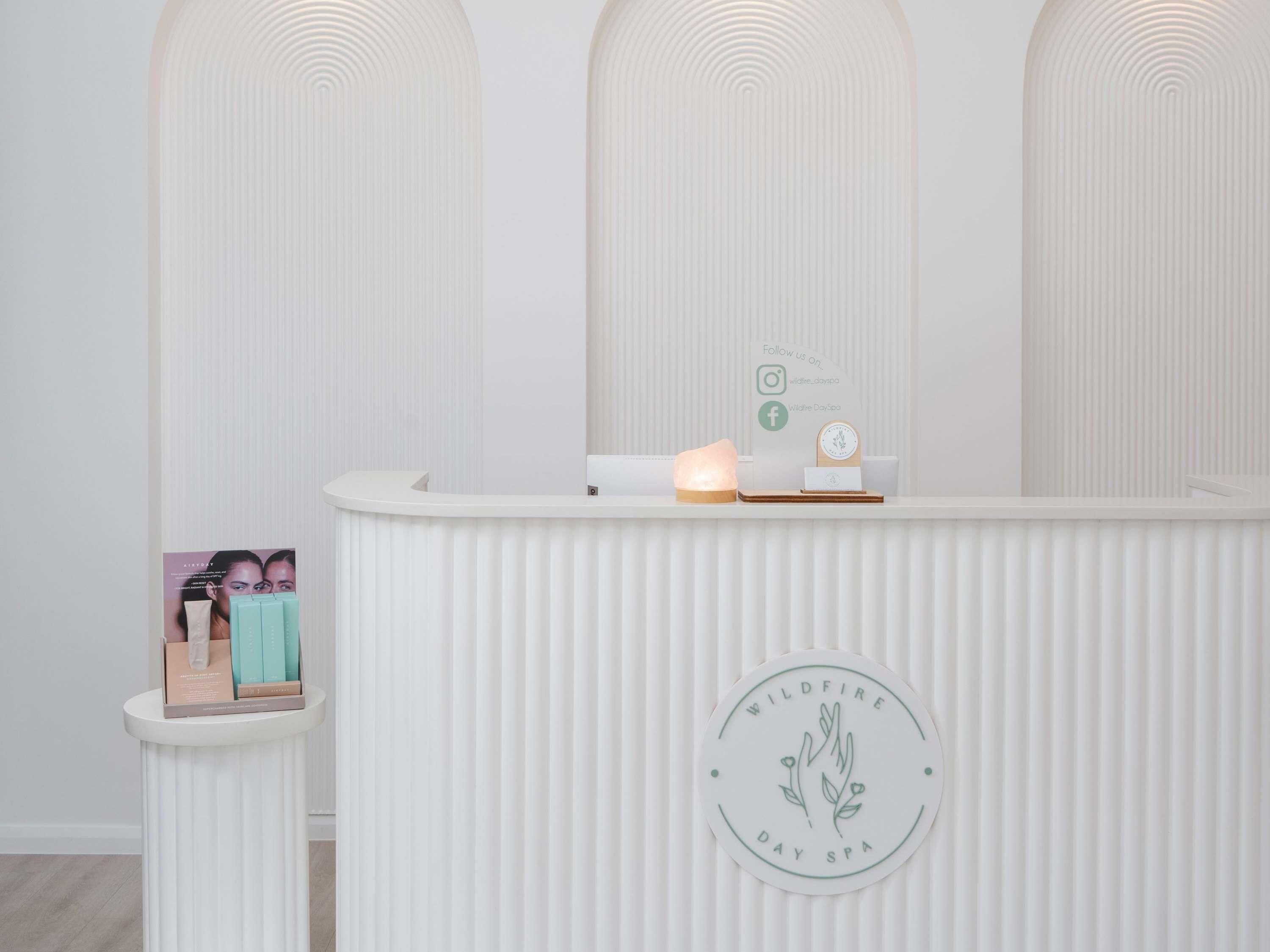 A reception desk with a logo, a small display case, and a wall-mounted clock.
