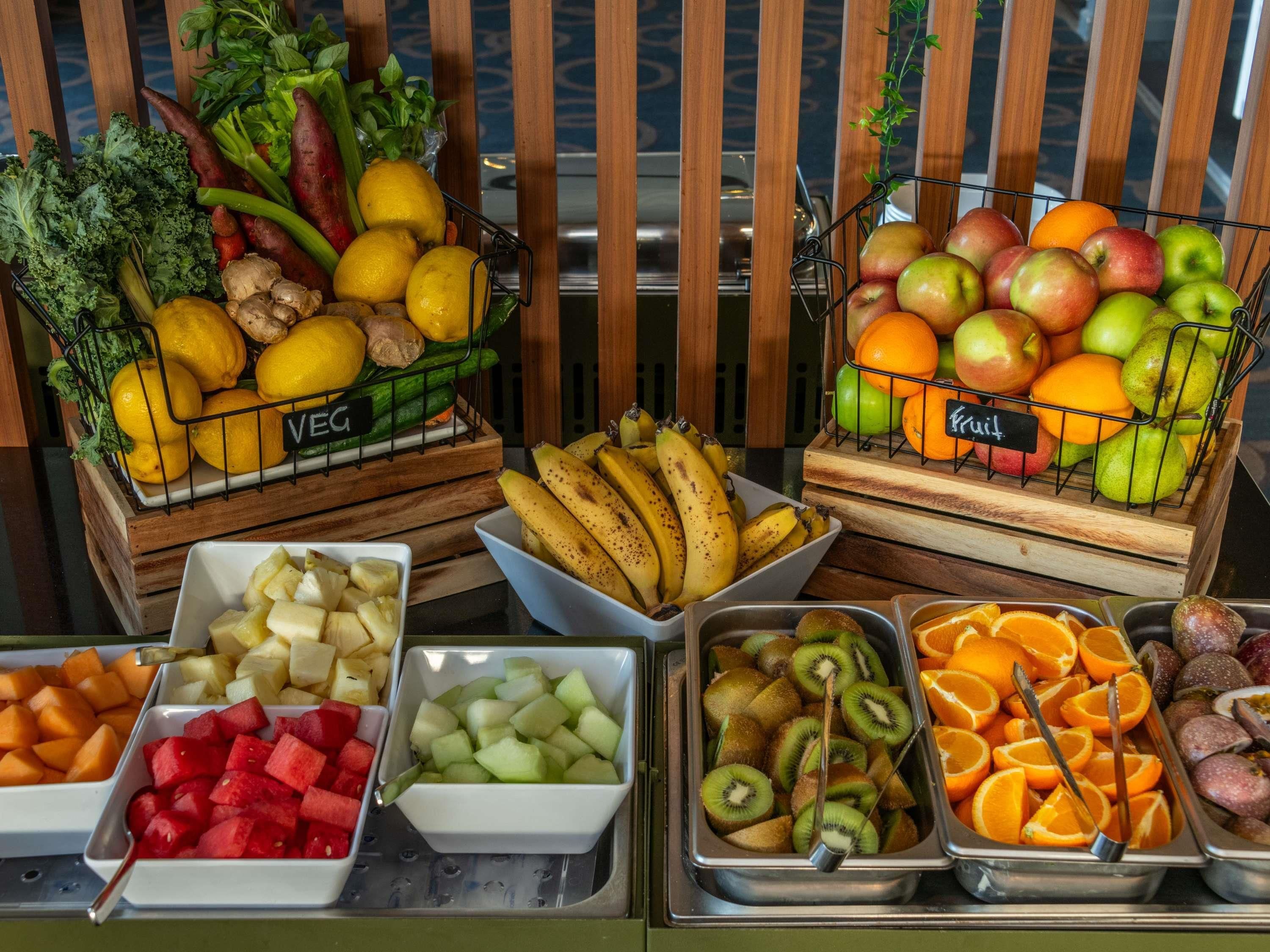 Esposizione di frutta e verdura con diversi tipi di prodotti disposti in vassoi e cesti.