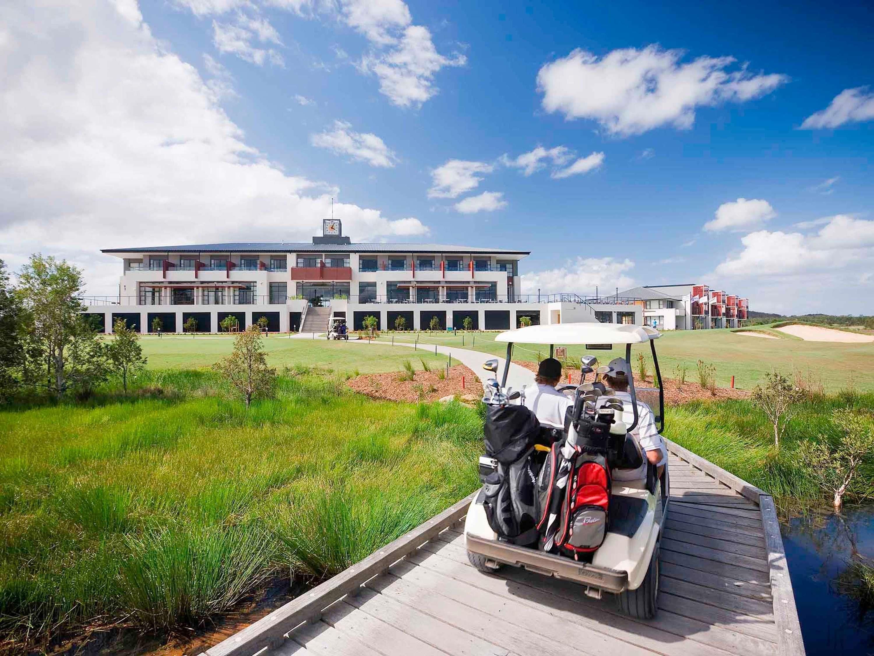 A golf course with a clubhouse, a wooden dock, and a golf cart.