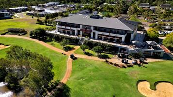 A large, modern building with multiple floors, surrounded by well-maintained lawns and a golf course.