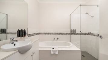 A modern bathroom with a large sink, a bathtub, and a glass shower enclosure.