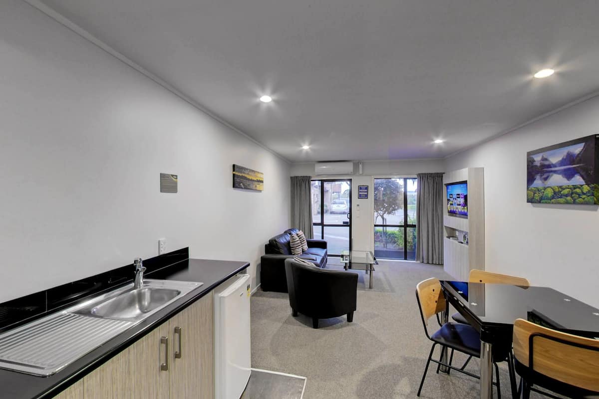 Una cocina moderna con un lavamanos, una zona de comedor con mesa y sillas, y una sala de estar con sofá.