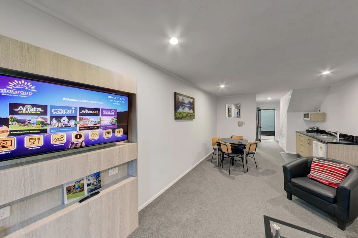 Una sala de estar moderna con televisor de pantalla plana, comedor y cocina.