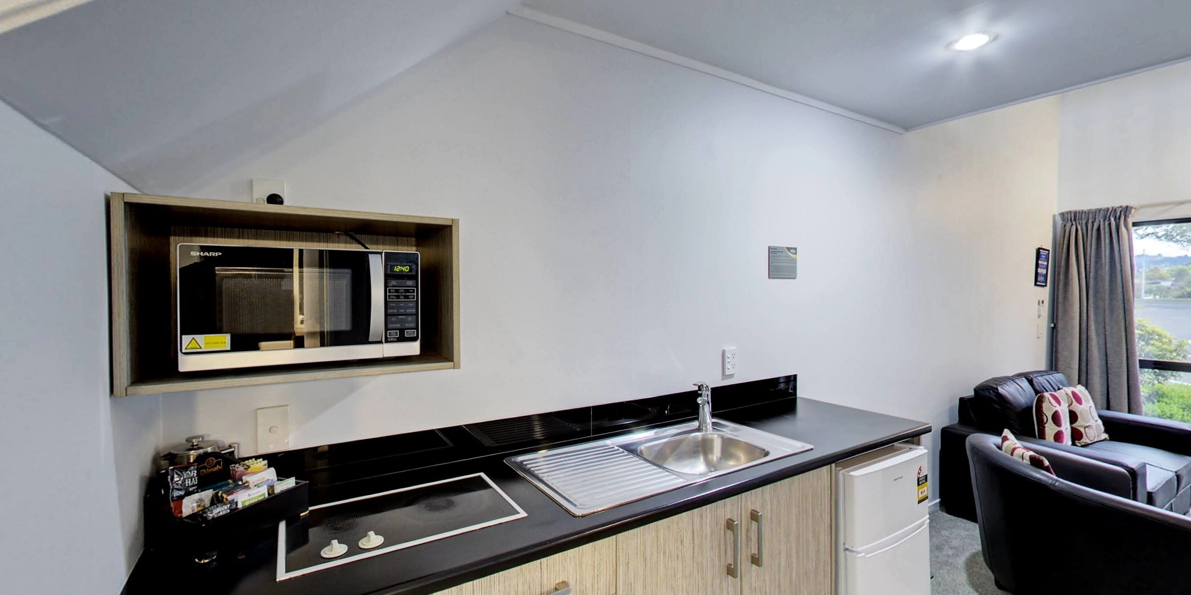 A compact kitchenette with a microwave, sink, and a small refrigerator.