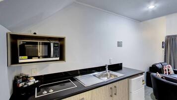 A compact kitchenette with a microwave, sink, and a small refrigerator.