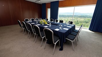 Uma sala de conferências com uma mesa comprida, cadeiras e vista para a paisagem através de amplas janelas.