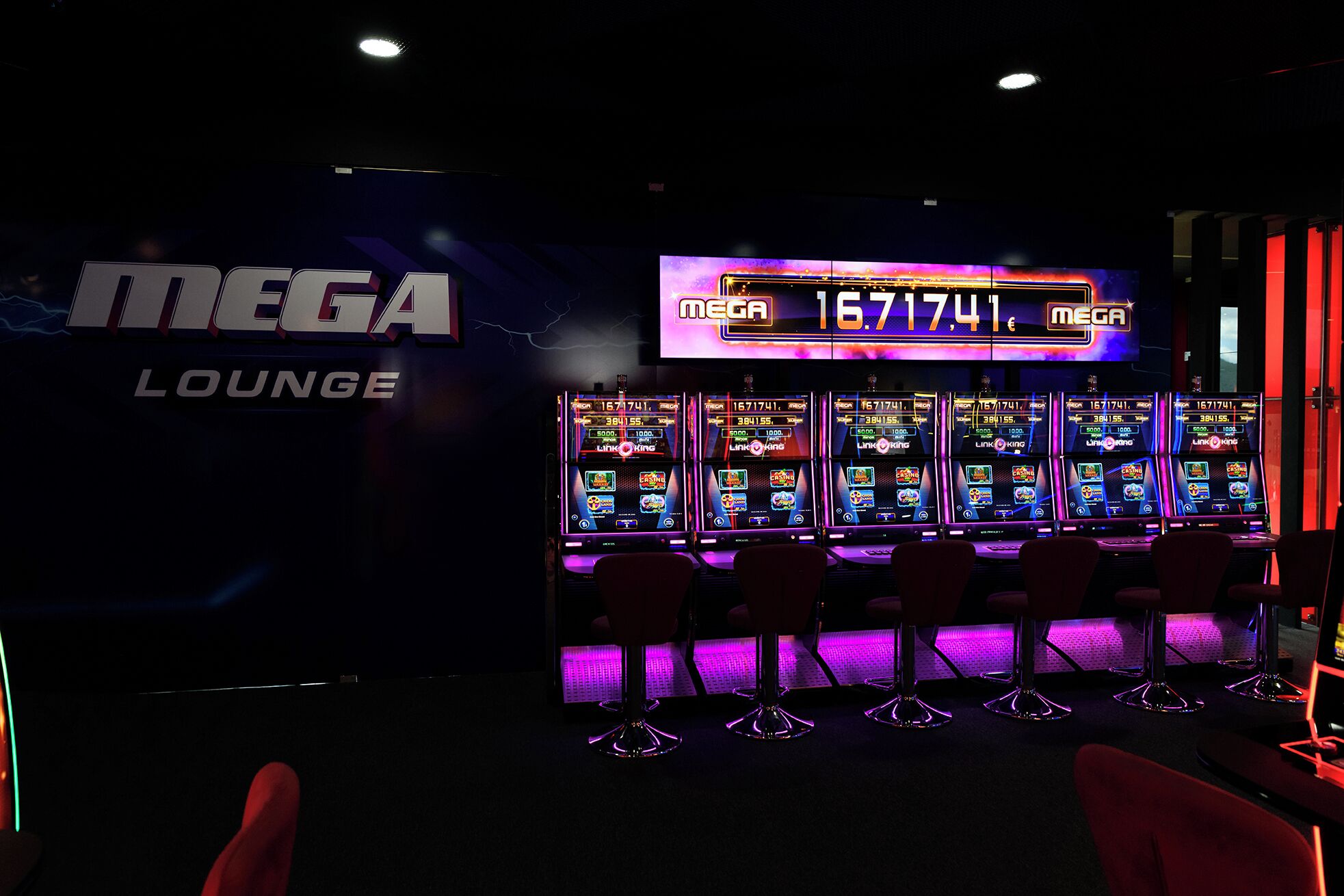 A gaming lounge with multiple slot machines and a neon sign displaying 'MEGA LOUNGE'.