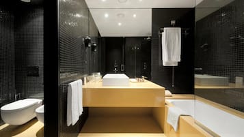 Un baño moderno con un espejo grande, una bañera y un inodoro.