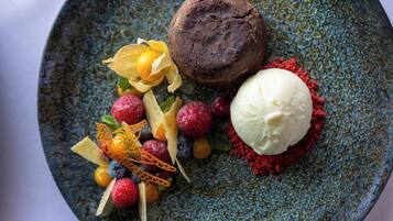A dessert plate with a chocolate cake, ice cream, and assorted berries and fruit garnishes.