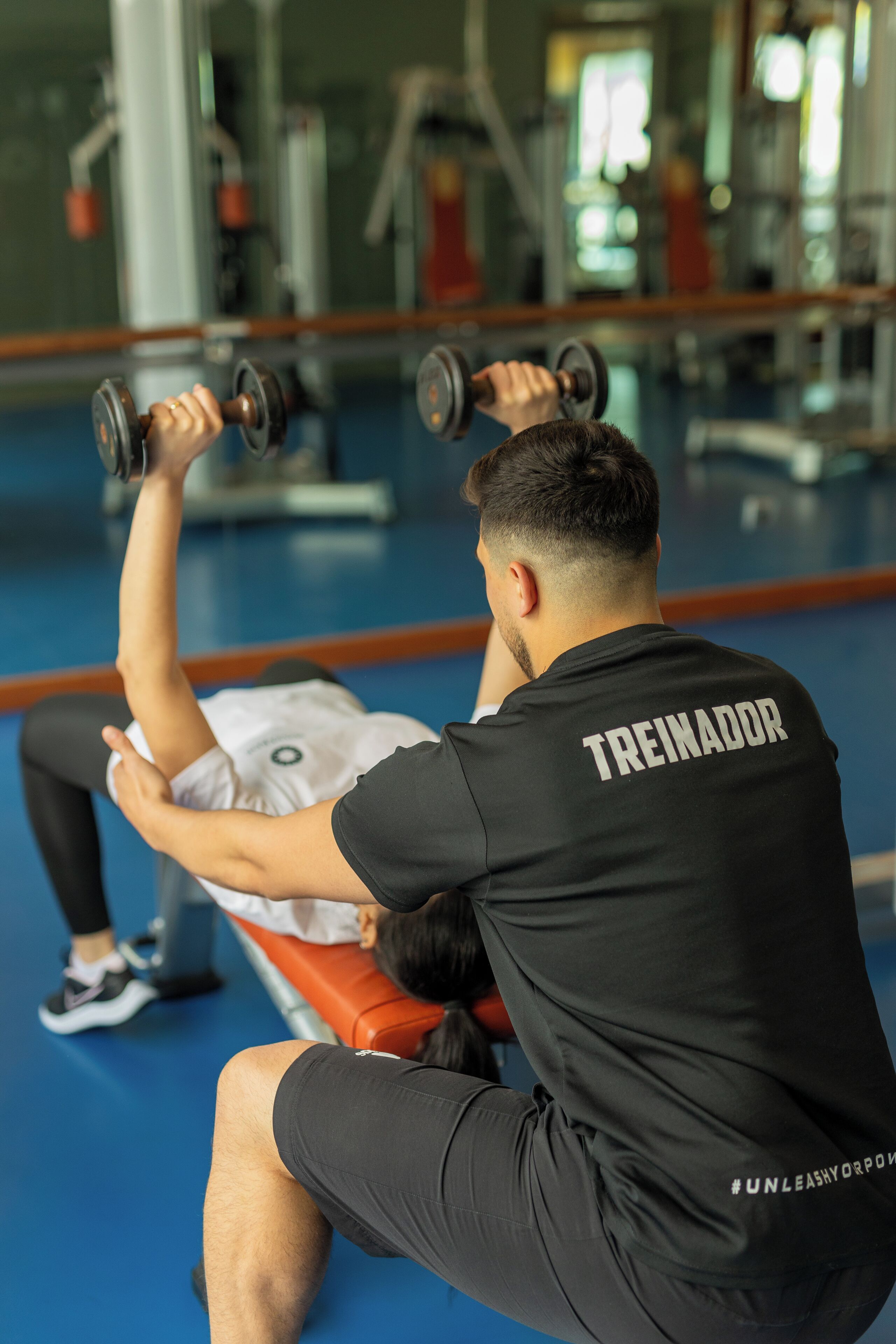 A gym with a person performing a bench press exercise.