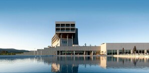 A modern hotel with a pool in front, featuring a unique architectural design with a prominent tower and a flat-roofed section. - Hotel Casino Chaves (Chaves)