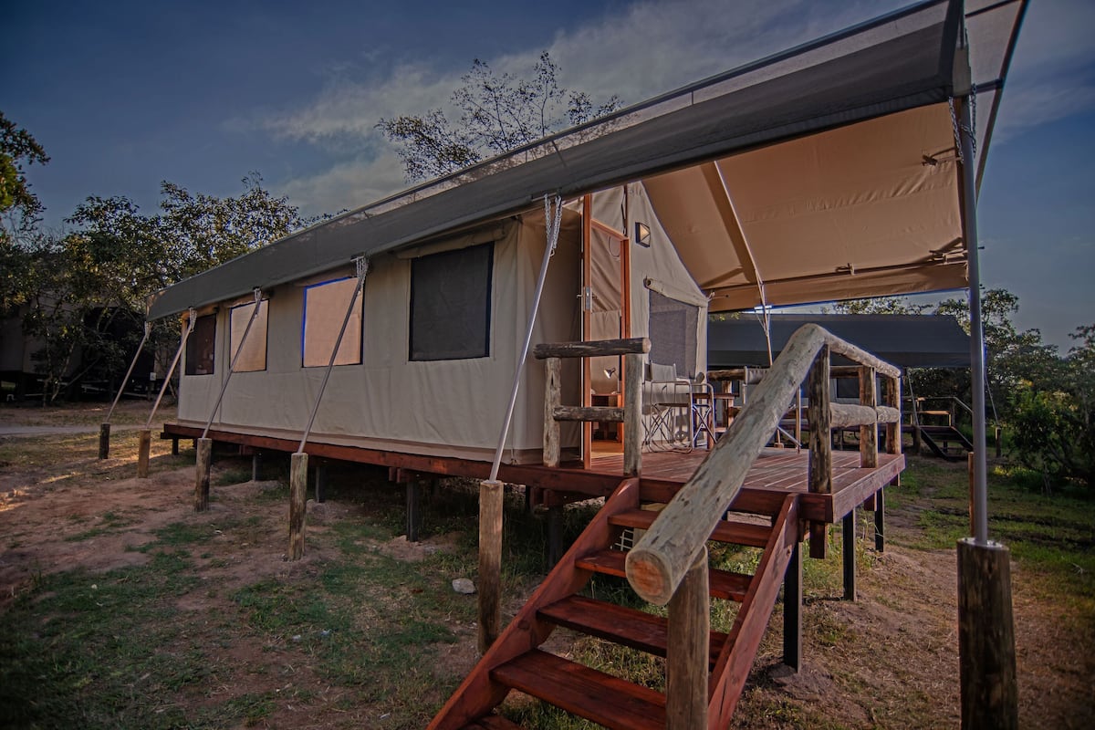 A safari tent with a wooden deck and a covered seating area.