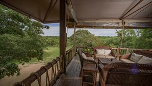 Terraza al aire libre con mobiliario de mimbre y vistas a un paisaje natural.