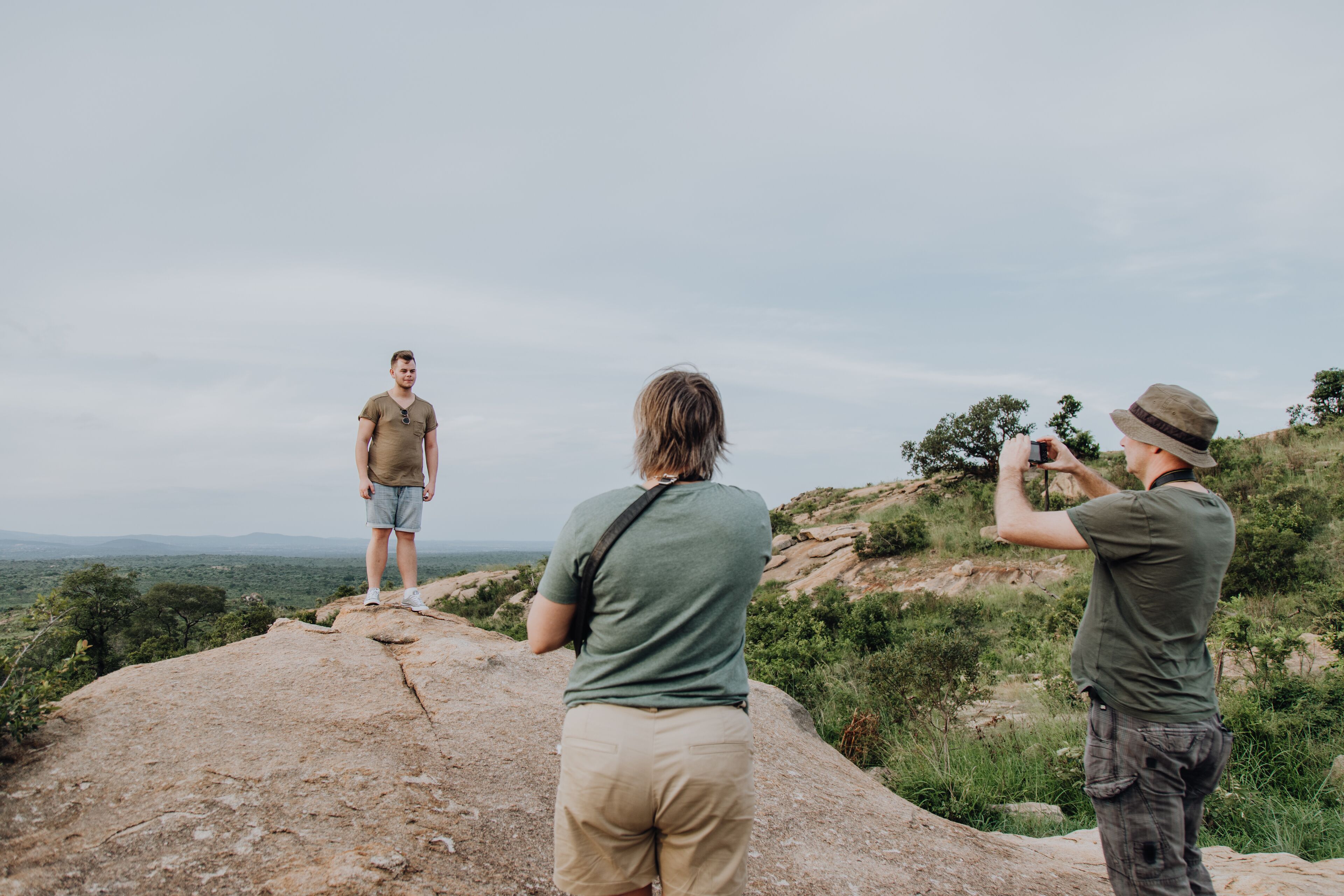Drei Personen auf einem Felsen mit Blick auf die Landschaft.