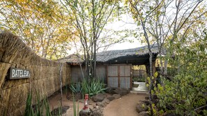 A rustic thatched-roof structure labeled "BATELEUR" with a dirt path leading to a covered area. - Taita Falcon Lodge (Livingstone)