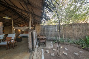 A rustic outdoor seating area with wooden furniture and a thatched roof. - Taita Falcon Lodge (Livingstone)