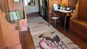 Interior de madera con un escritorio, una silla y un tapete con un diseño de caballo.