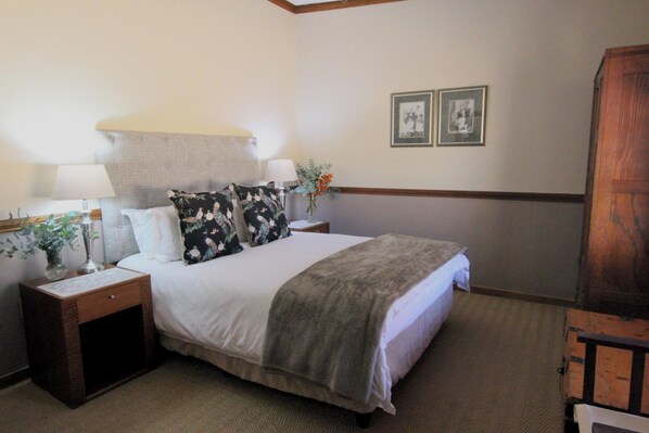 A neatly made bed with a white comforter and a gray throw blanket, flanked by two bedside tables with lamps and vases.