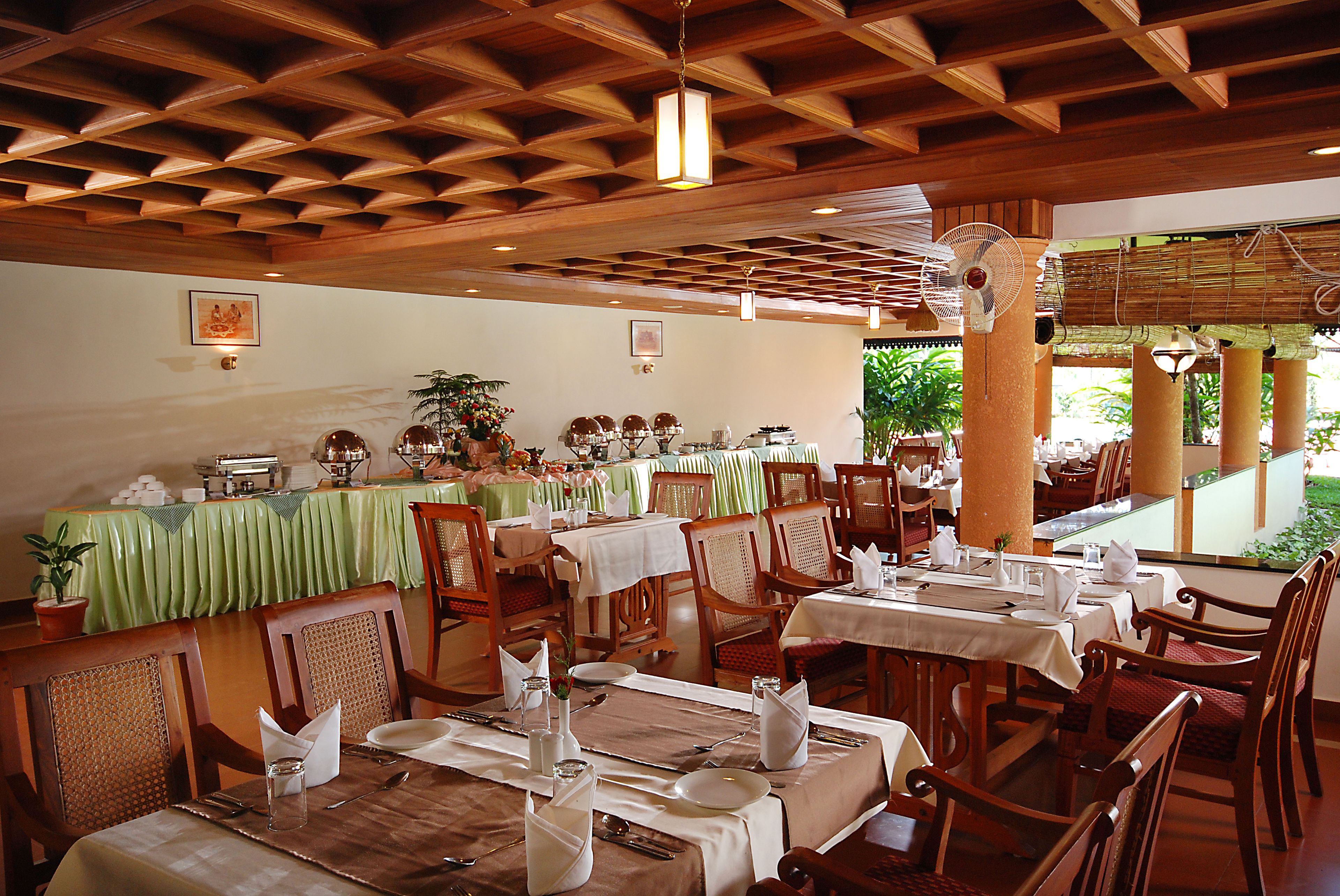 A restaurant with wooden ceiling beams, green tablecloths, and wooden chairs.
