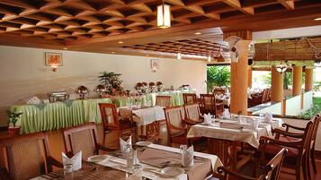 A restaurant with wooden ceiling beams, green tablecloths, and wooden chairs.