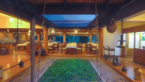 A restaurant with a central seating area, a hanging swing, and a view of the outdoors. - Greenwoods Thekkady - A Five Star Classified Resort (Peermade)