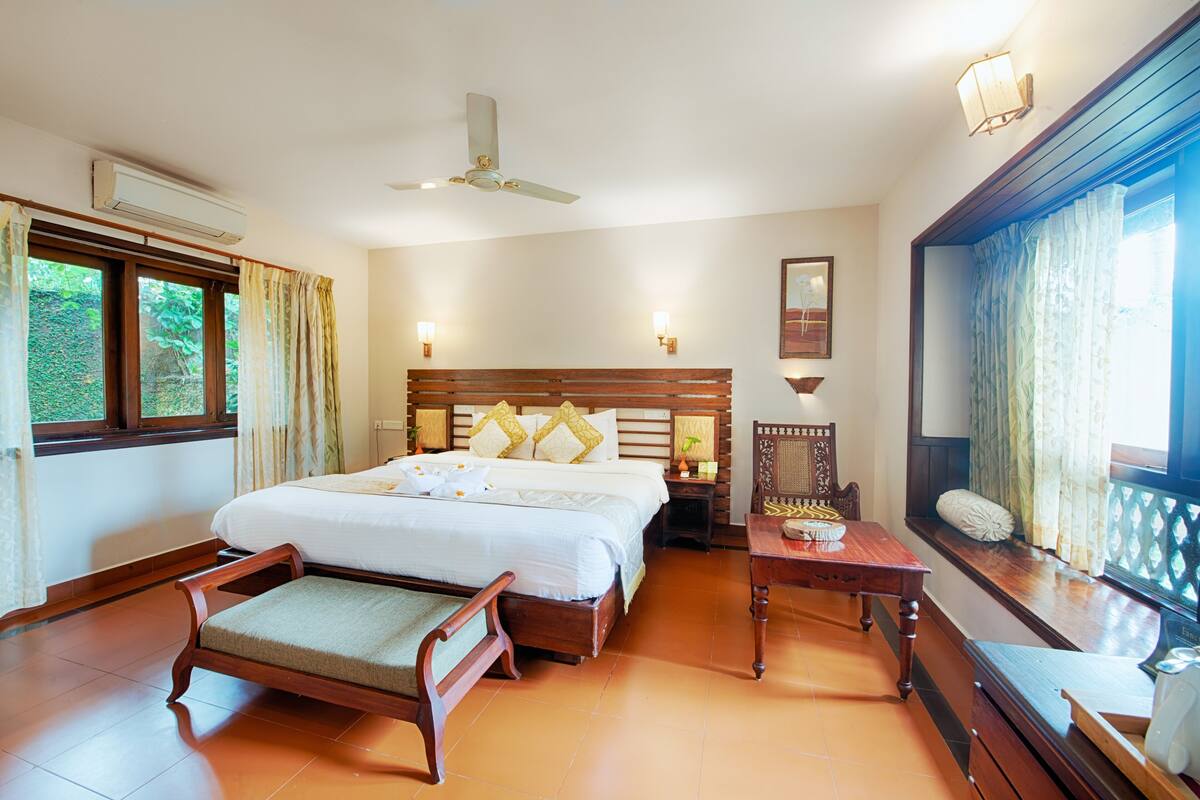 Un dormitorio con una cama grande, muebles de madera, un ventilador de techo y una ventana con cortinas.