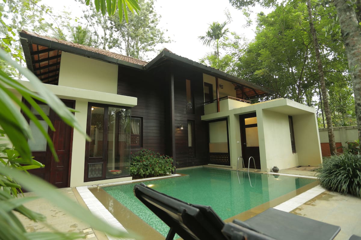 Una casa moderna con piscina, ventanas amplias y un balcón.