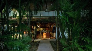 Ein Weg führt zu einem Restaurant mit traditionellem Dach und Innenbereich.