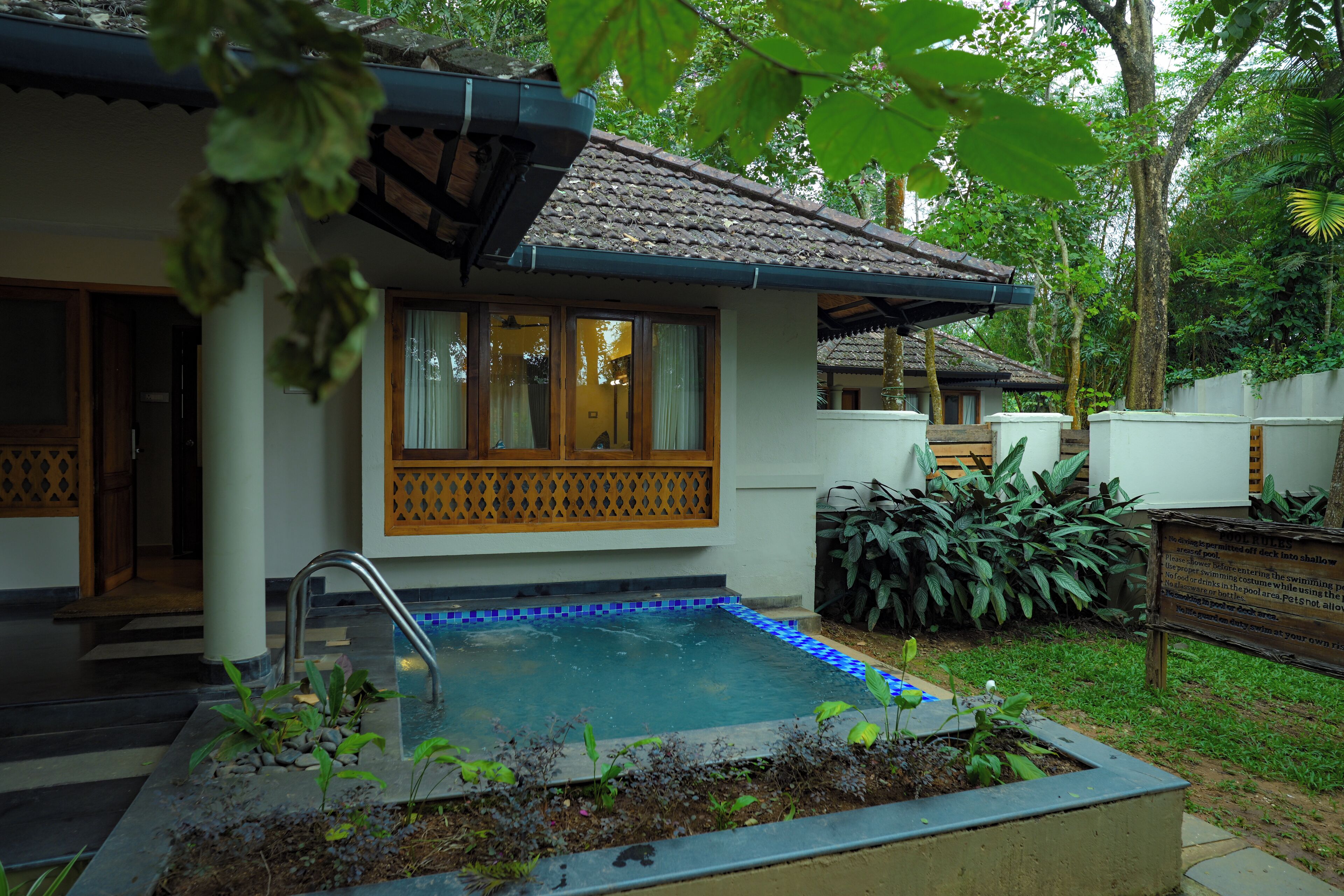 A house with a swimming pool, surrounded by lush greenery.