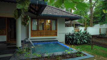 A house with a swimming pool, surrounded by lush greenery.