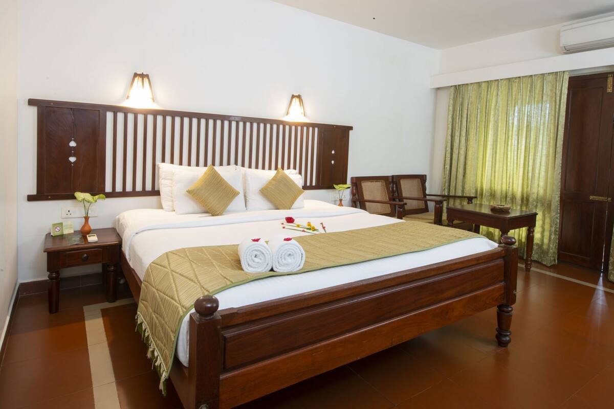 Una habitación de hotel con una cama de madera, dos mesitas de noche, un escritorio y una silla.