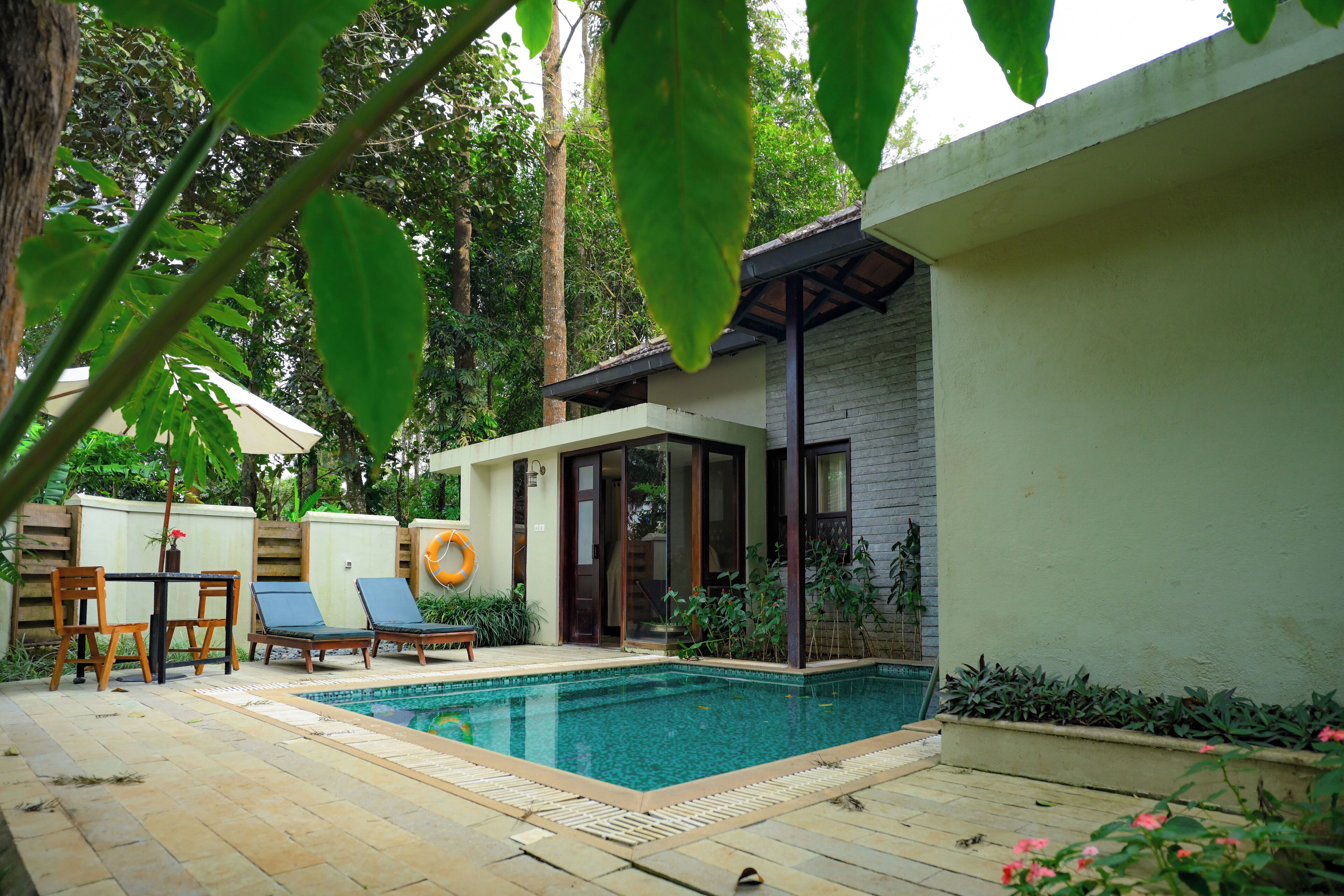 A pool area with lounge chairs, a table, and a covered seating area.