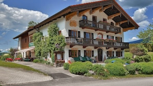 A traditional Alpine-style building with a balcony, a signboard, and a garden area. - Landhotel Binderhausl (Inzell)