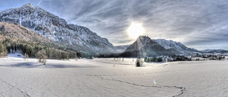 A snow-covered landscape with mountains and a clear sky.