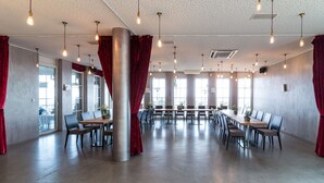 Une salle de conférence spacieuse, dotée d’une longue table, de nombreuses chaises et de luminaires suspendus.