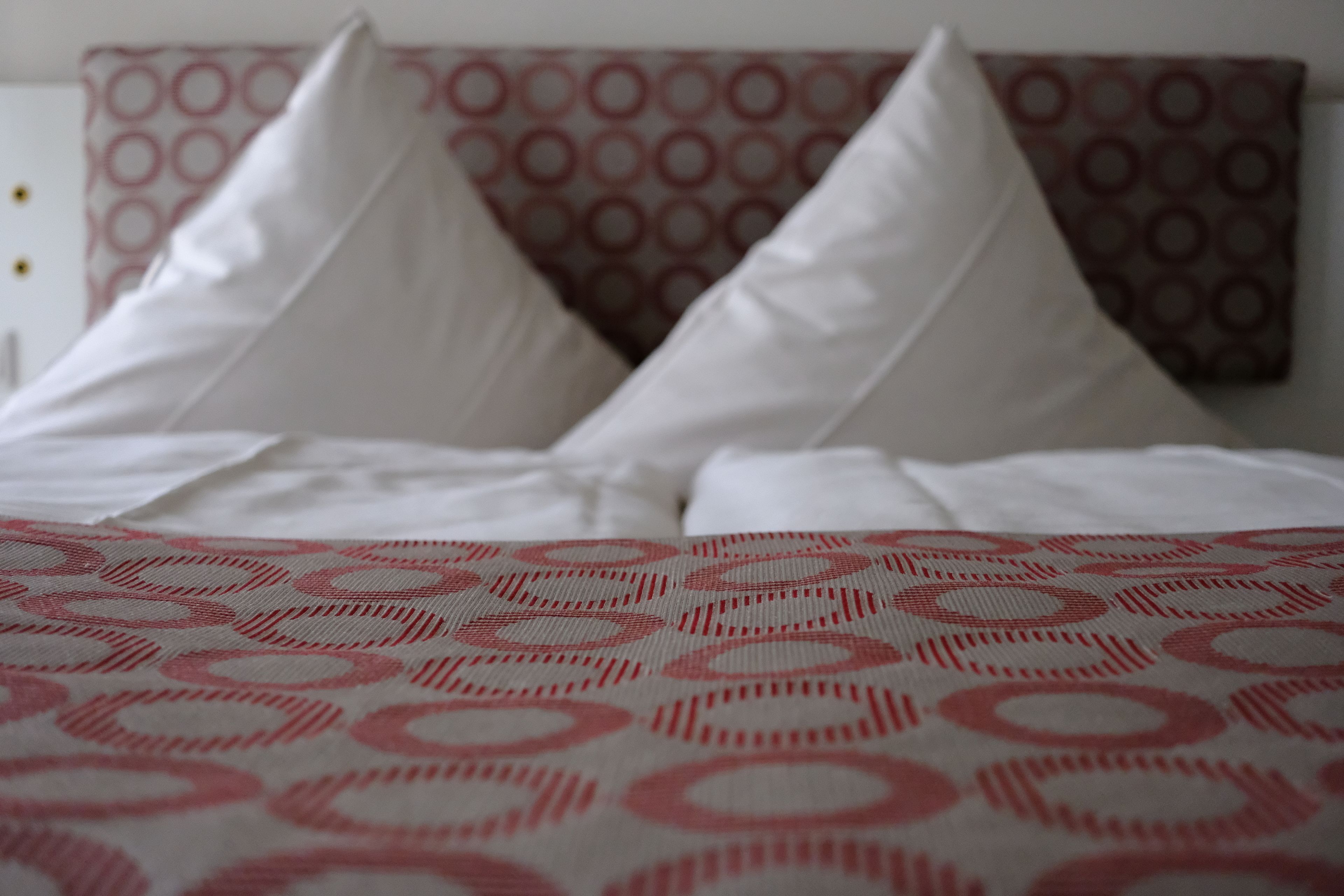 A bed with white pillows and a patterned bedspread.