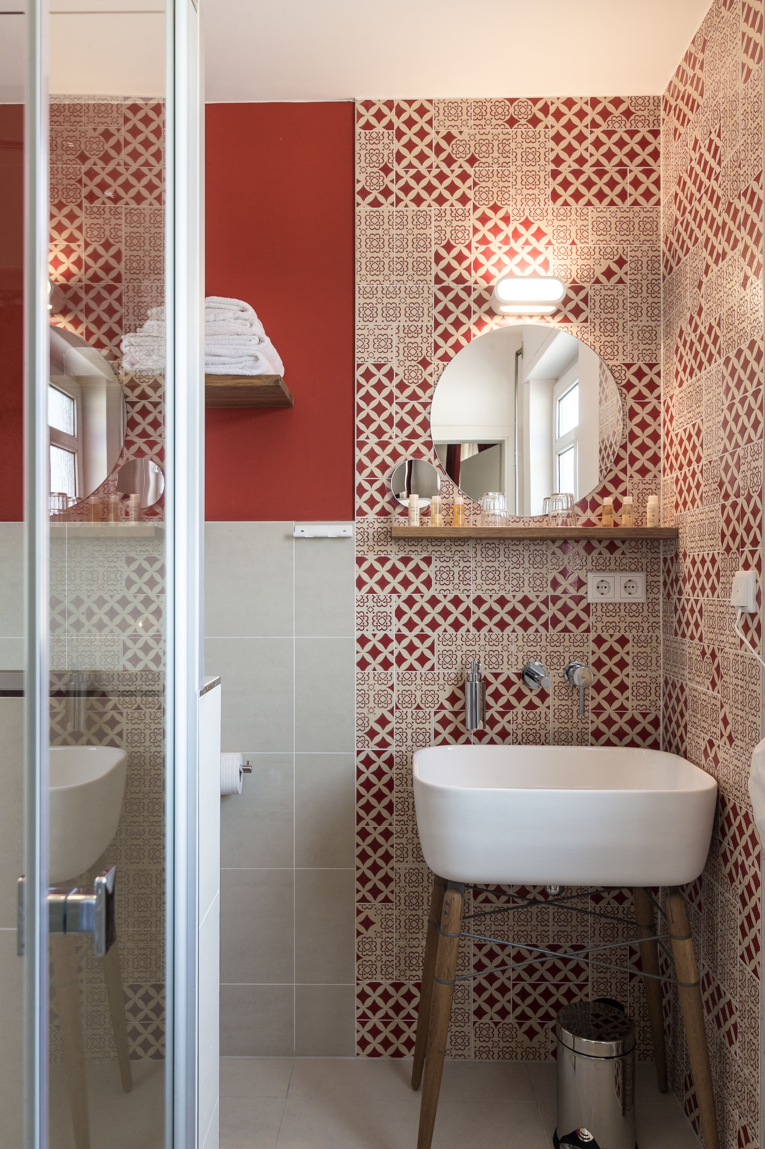 Un baño con baldosas estampadas, un lavabo, un espejo y una zona de ducha.