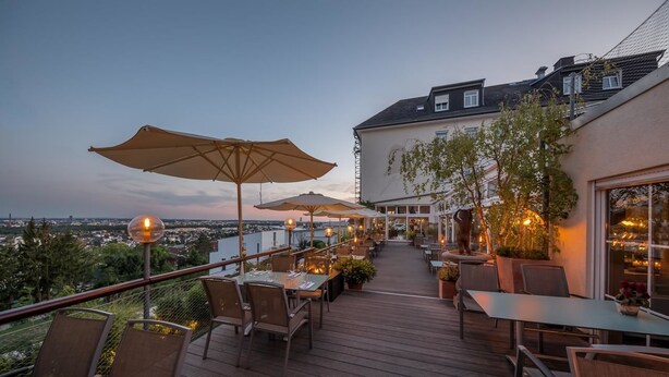 Une terrasse extérieure avec des tables et des chaises, des parasols et des plantes en pot.