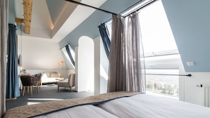 Une chambre d’hôtel moderne avec un grand lit, un bureau et une chaise. La fenêtre offre une vue sur la ville.